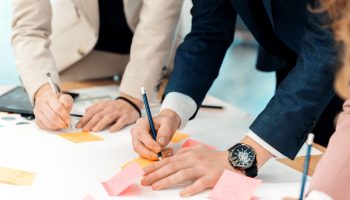Business meeting in an office, close view of workers taking notes on sticky papers