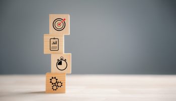 Wooden block step on a table with Action Plan, Goal, and Target icons. Success and business target concept. Company strategy and project management for financial growth.
